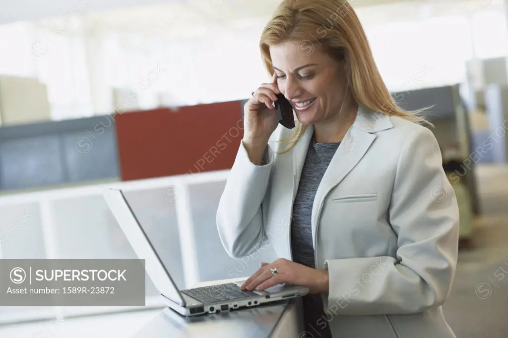 Businesswoman with laptop and cell phone