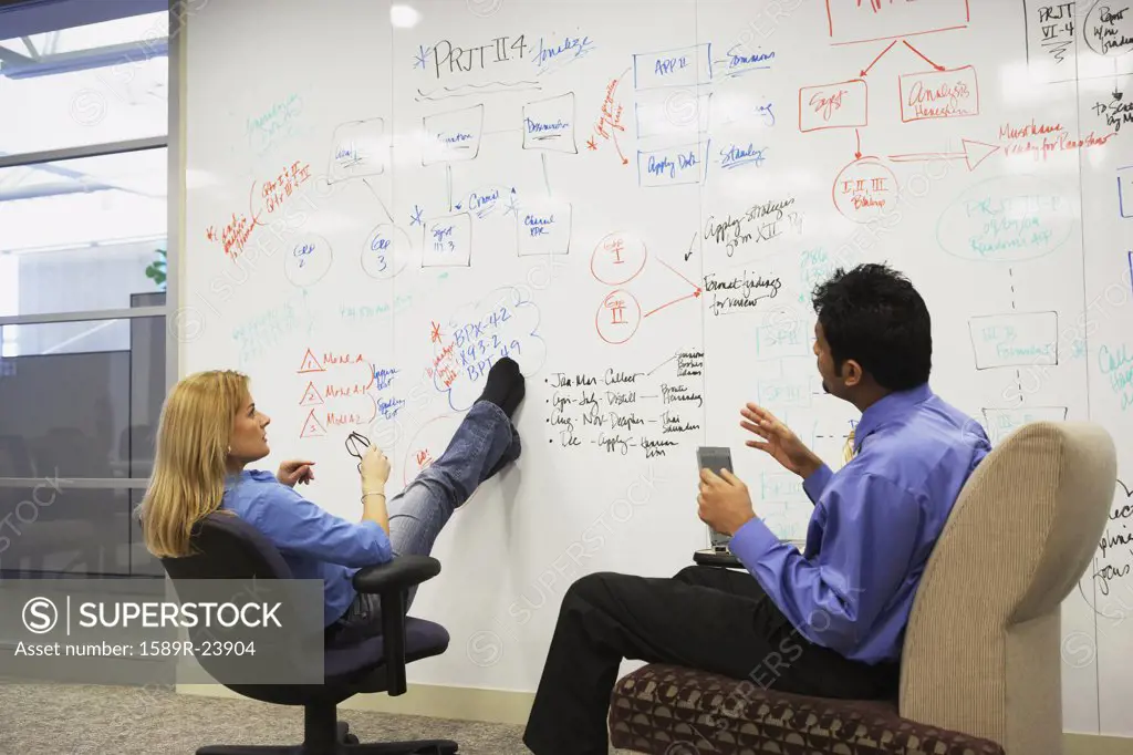 Businesspeople having a meeting in front of a whiteboard wall