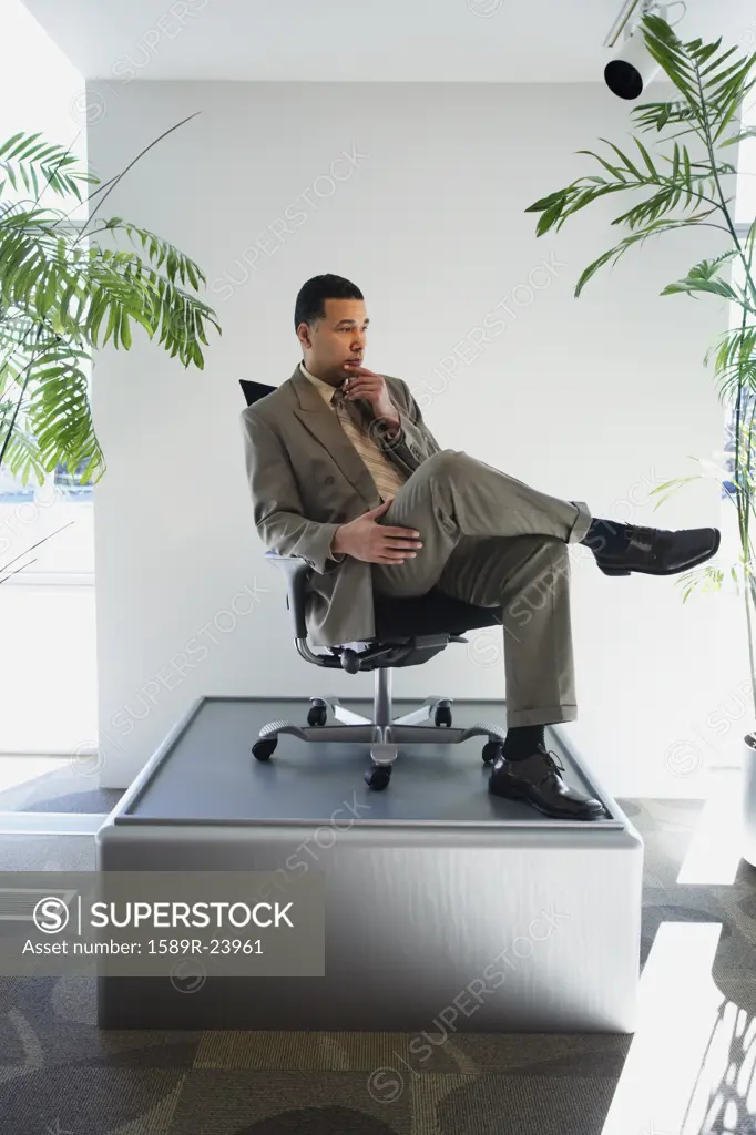 African American businessman sitting in chair on pedestal