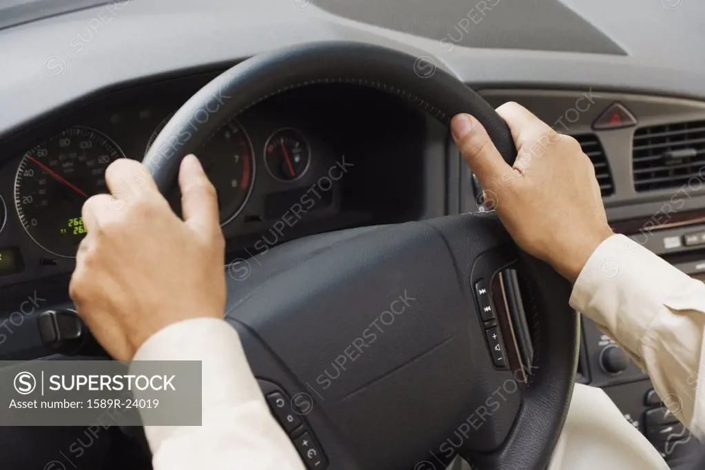 Close up of man's hands on steering wheel