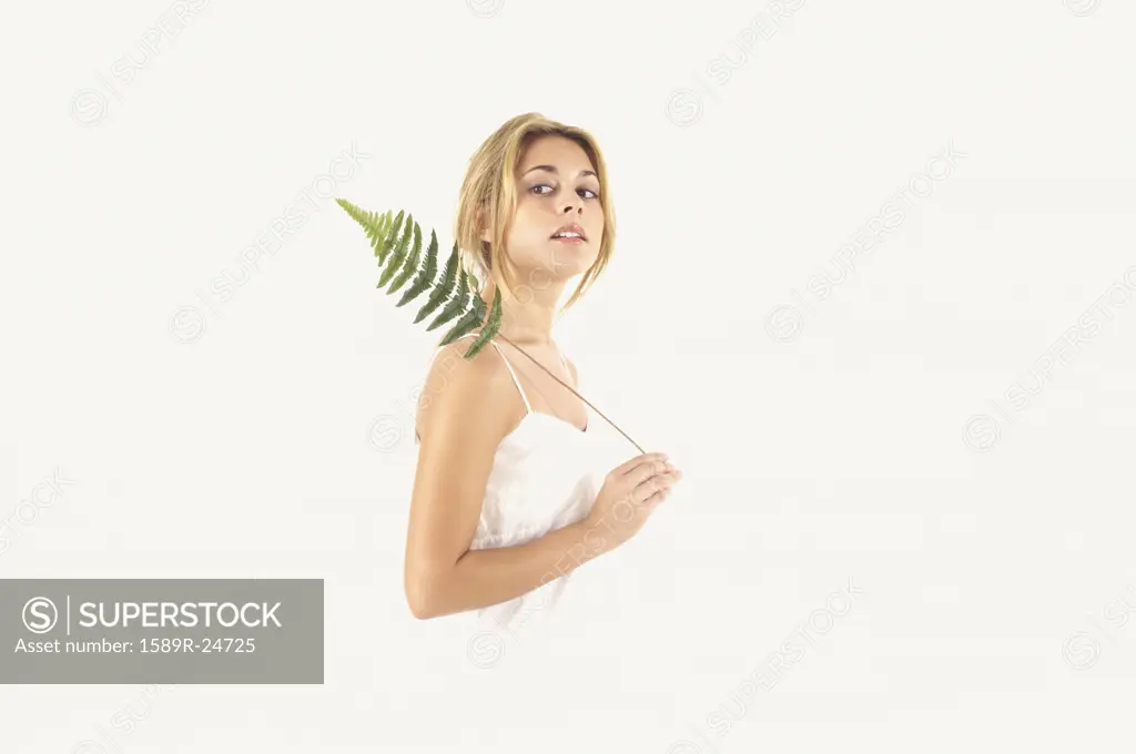 Studio shot of woman holding fern leaf