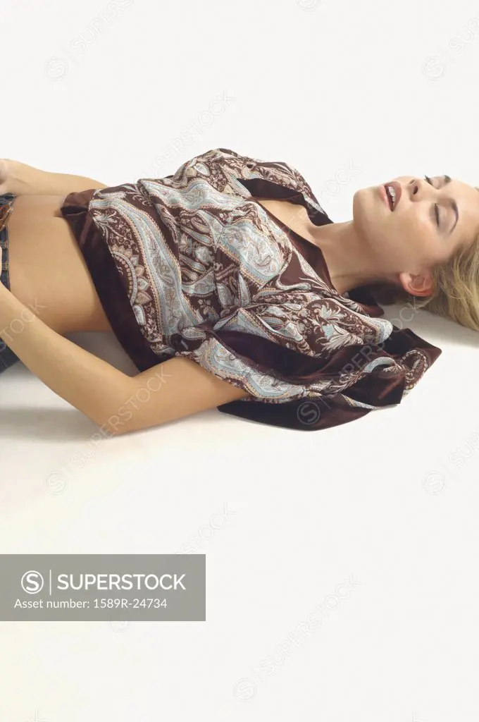 Studio shot of woman lying on floor with eyes closed