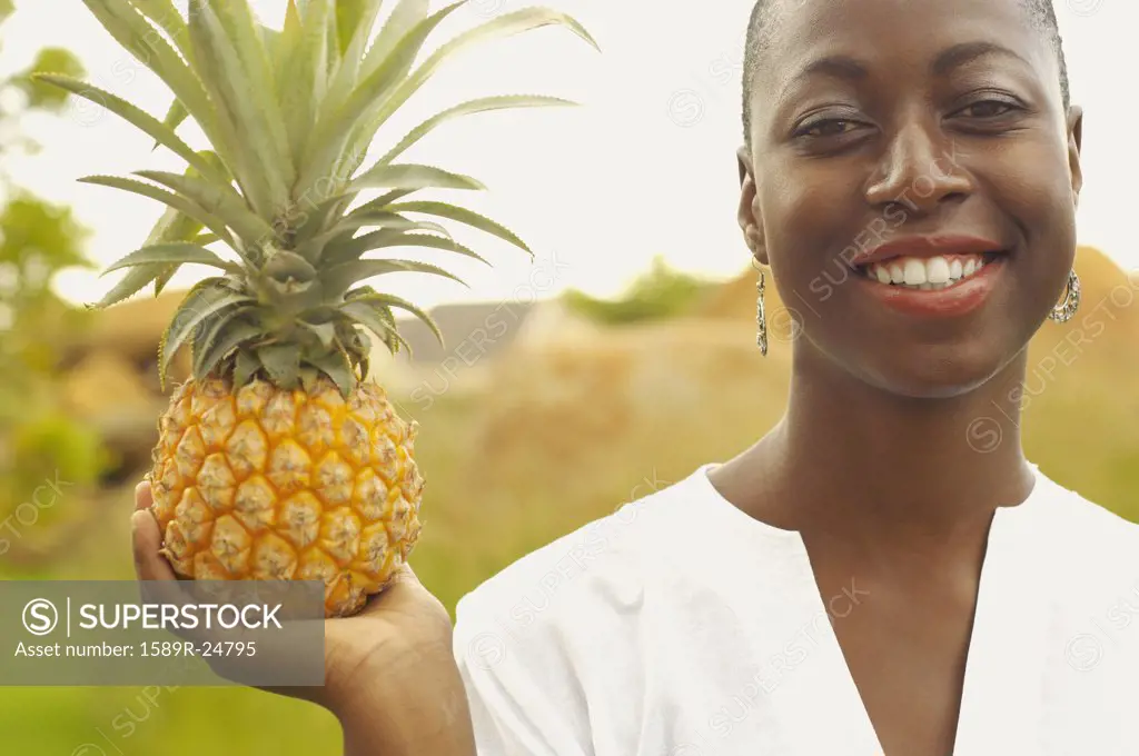 African American woman holding pineapple outdoors
