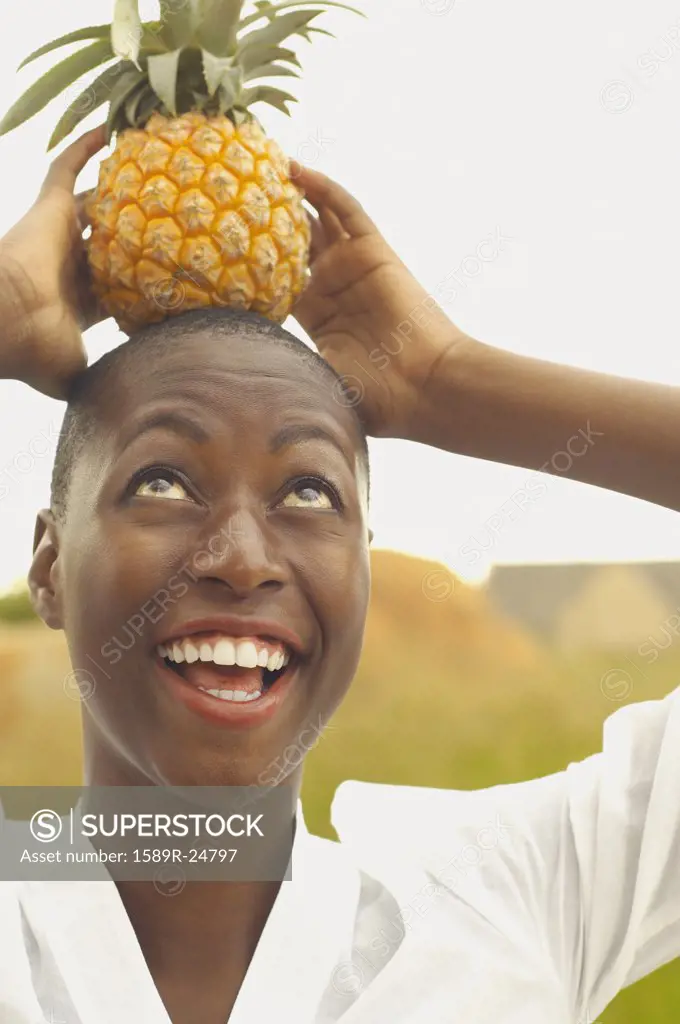 African American woman balancing pineapple on head
