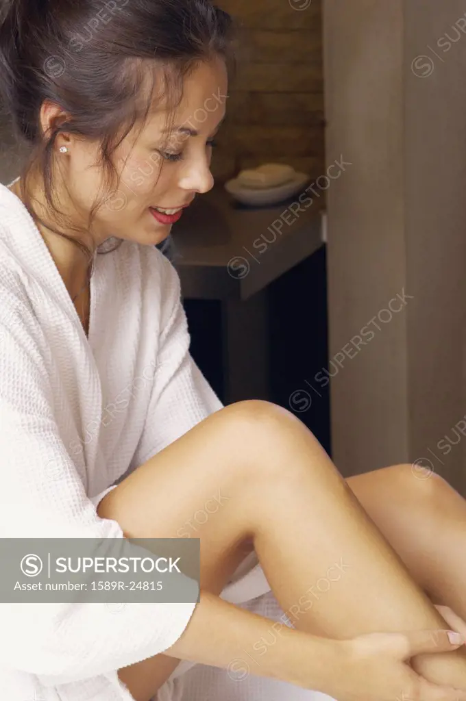 Woman in bathrobe applying lotion