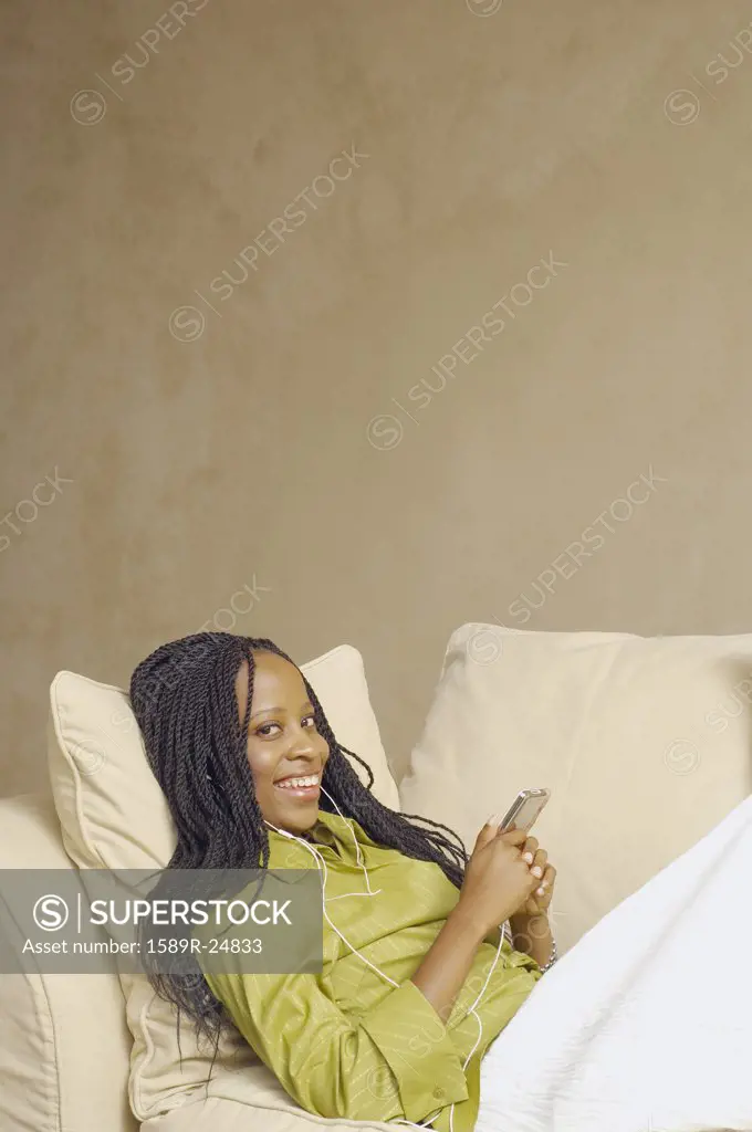 African American woman with MP3 player on sofa