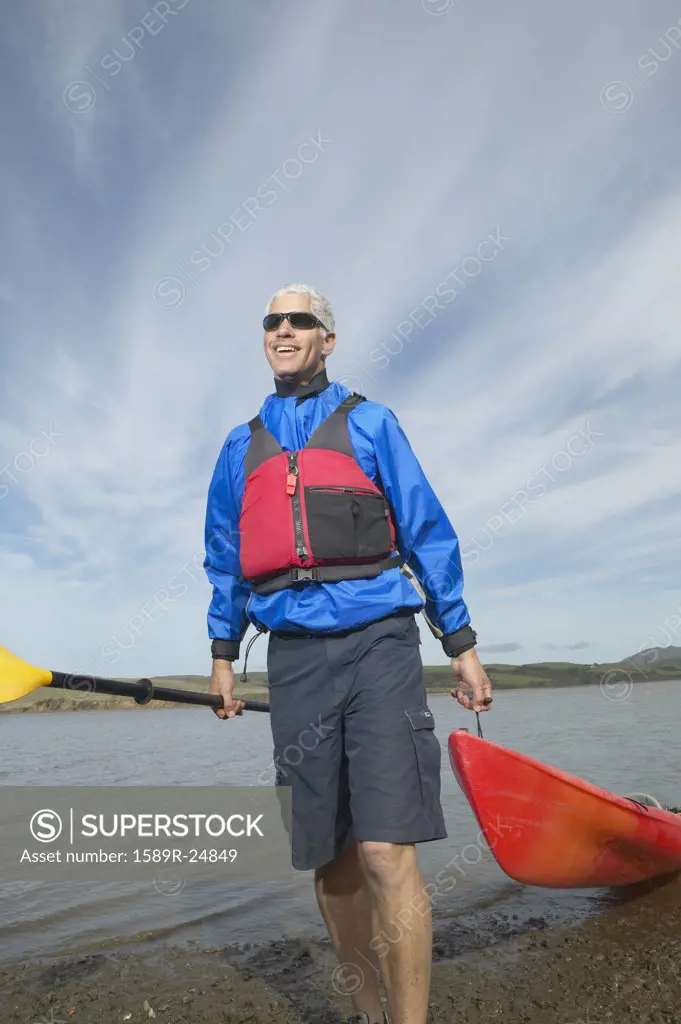 Middle-aged man pulling kayak out of the water, California, United States