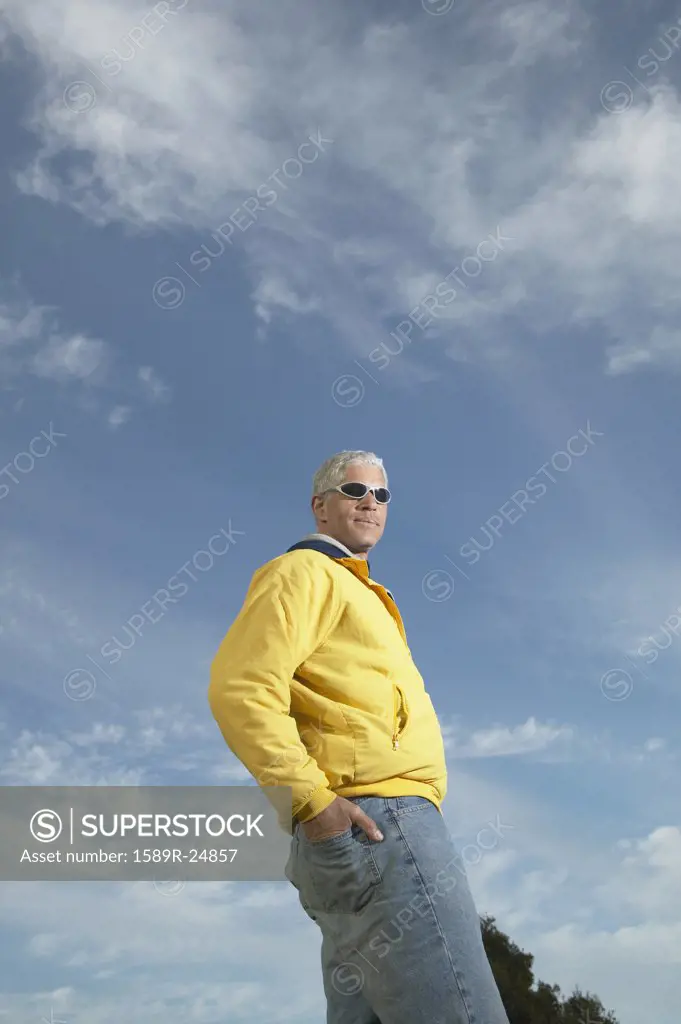 Middle-aged man standing under a blue sky with his hand in his back pocket, California, United States