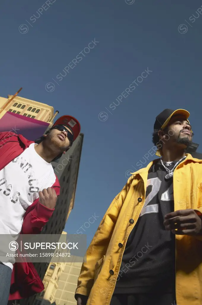 Low angle view of two young African men standing in urban area, Oakland, California, United States