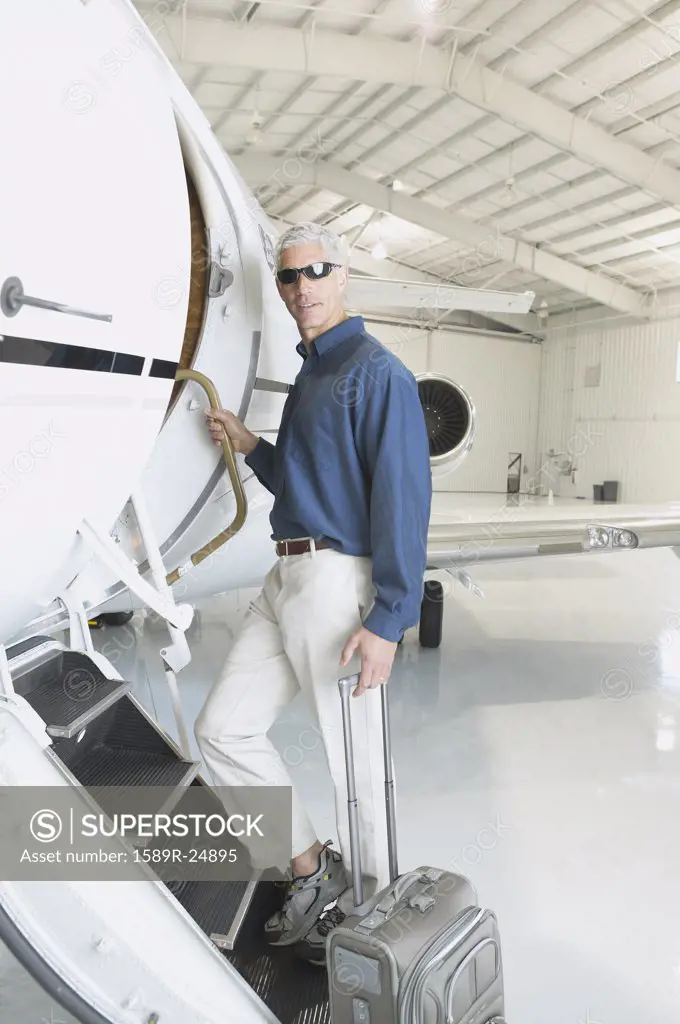 Man with suitcase boarding airplane in hanger, Nobato, California, United States