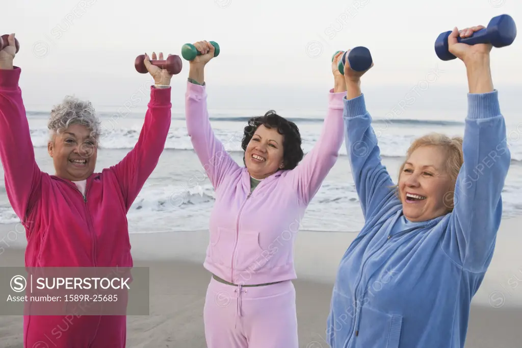 Group of senior woman lifting weights at the beach