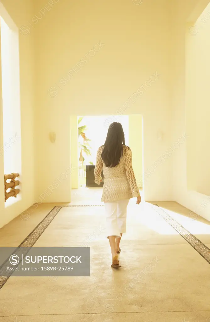 Woman walking down sunlit hallway, Los Cabos, Mexico