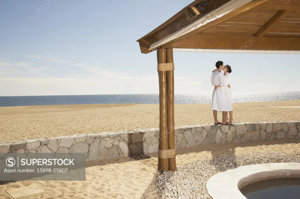 Couple in bathrobes kissing at beach, Los Cabos, Mexico