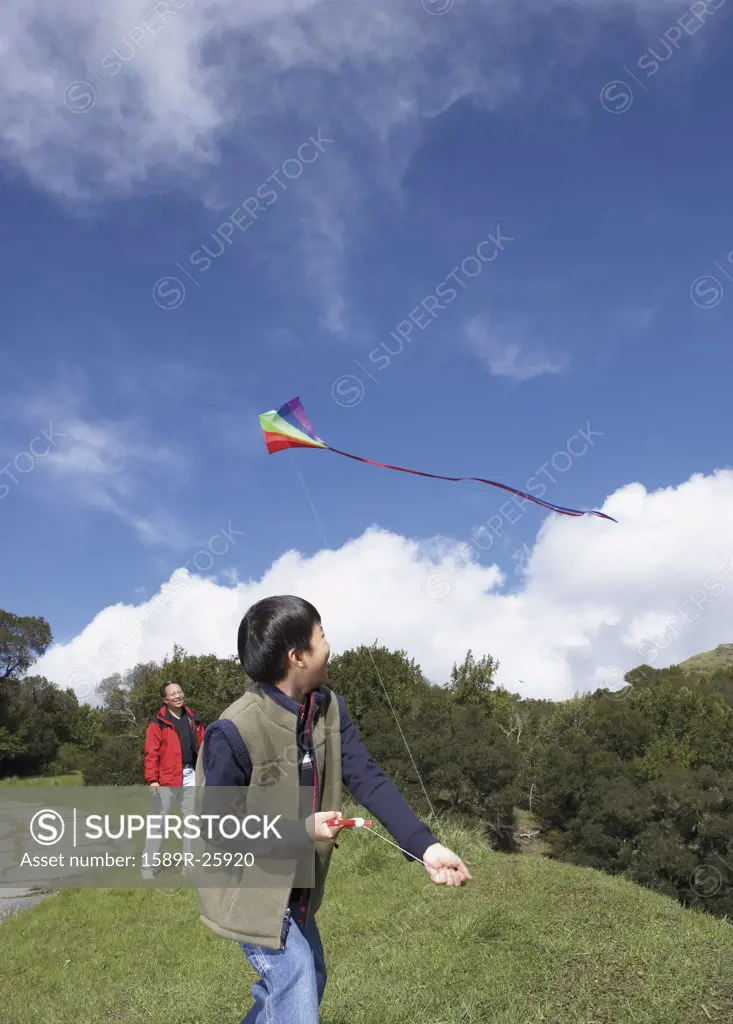 Asian father and son flying a kite