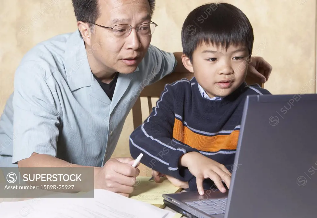 Asian father helping young son with homework