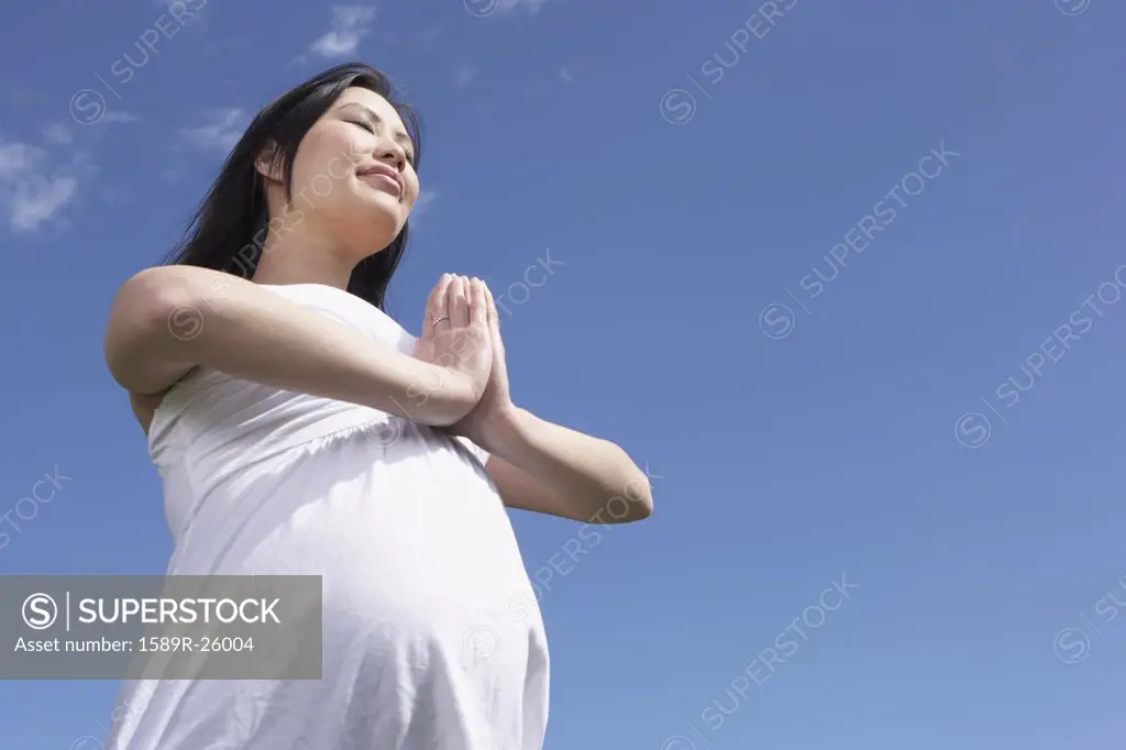 Pregnant Asian woman doing yoga outdoors