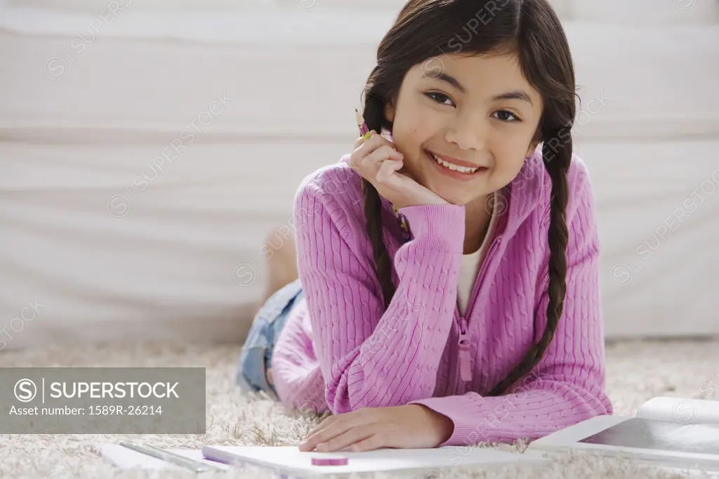 Young Hispanic girl doing homework on the floor