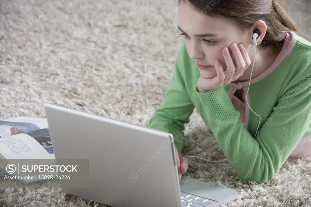 Young girl lying on the floor with laptop