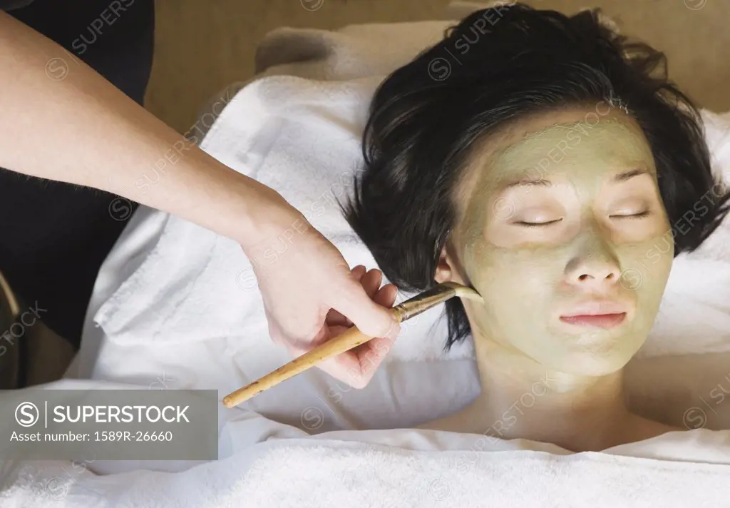 Asian woman receiving spa facial treatment