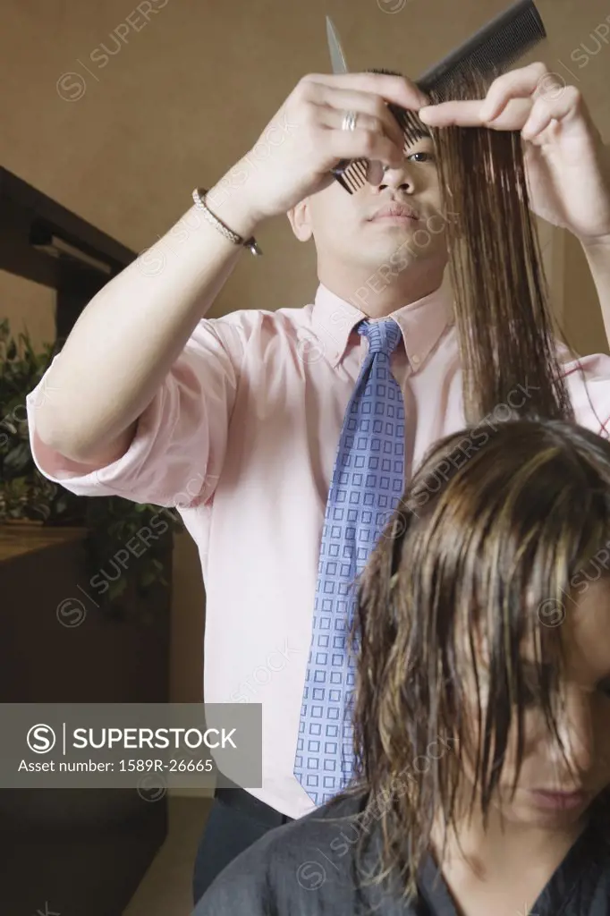 Asian male hairstylist cutting hair