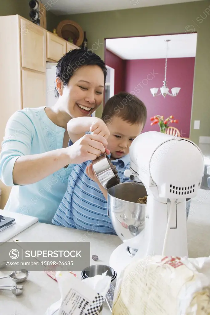 Asian mother and young son baking in kitchen