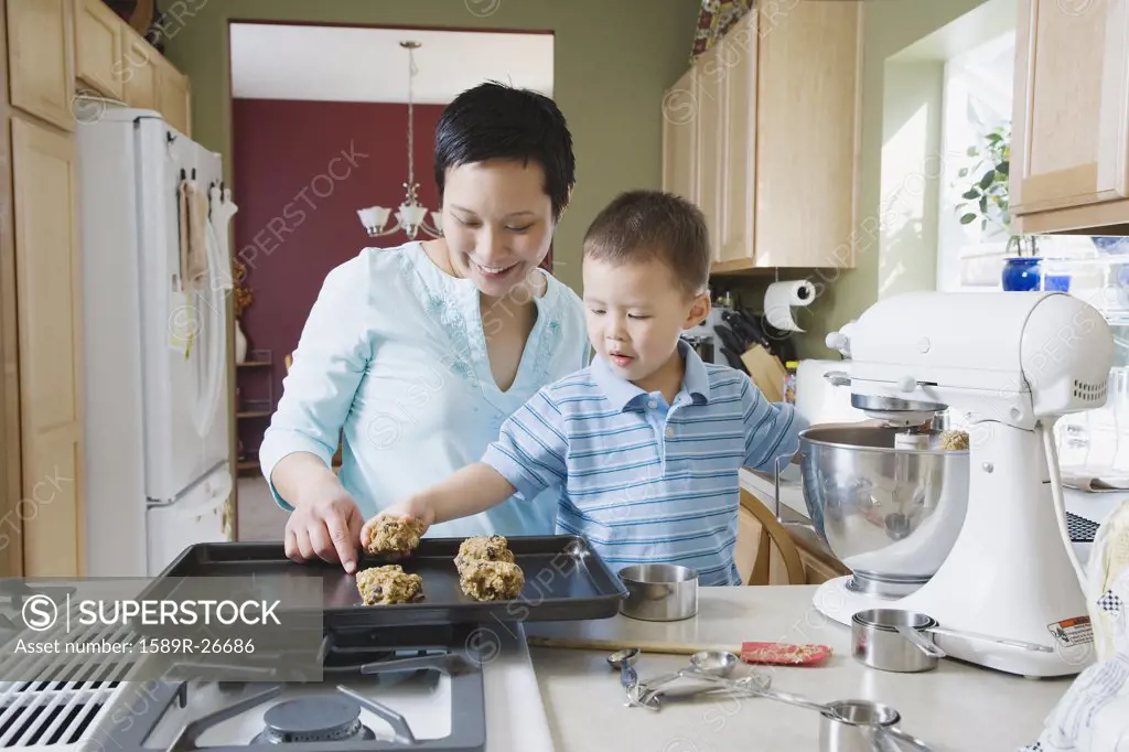 Asian mother and young son making cookies