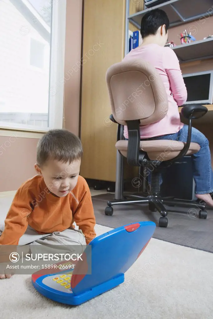 Woman working at home with young son