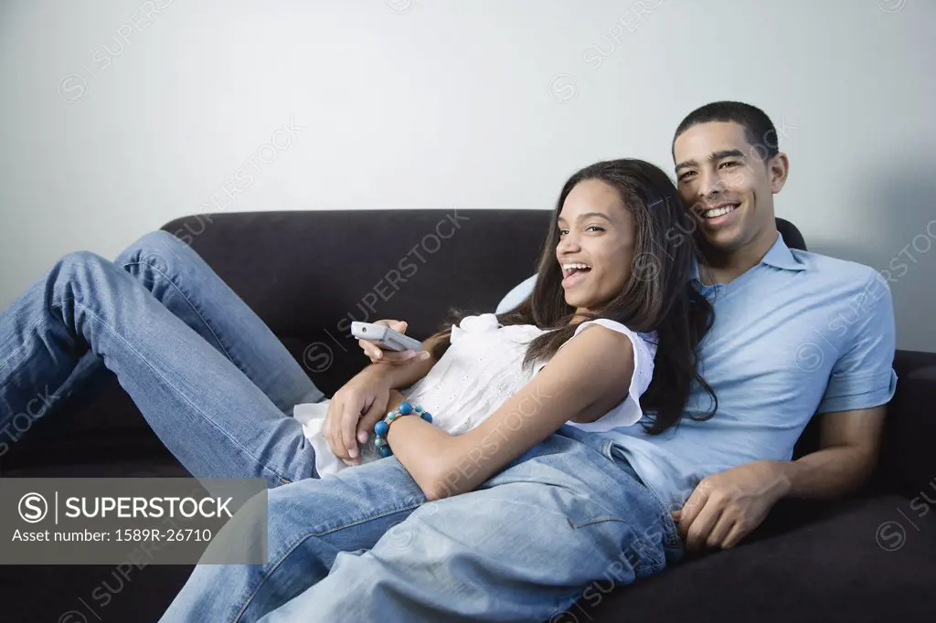 Young African couple watching television on sofa