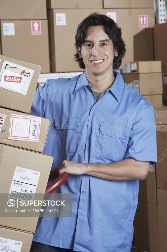 Hispanic male warehouse worker with stack of boxes