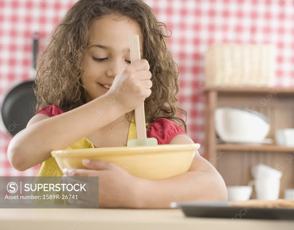 Young girl mixing batter in kitchen