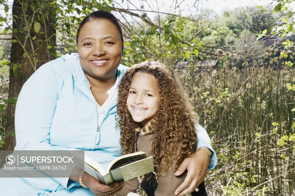 African mother and daughter reading outdoors