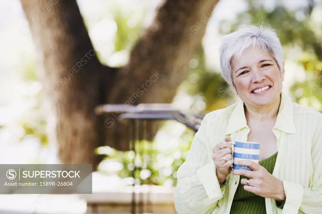 Middle-aged woman with coffee smiling outdoors