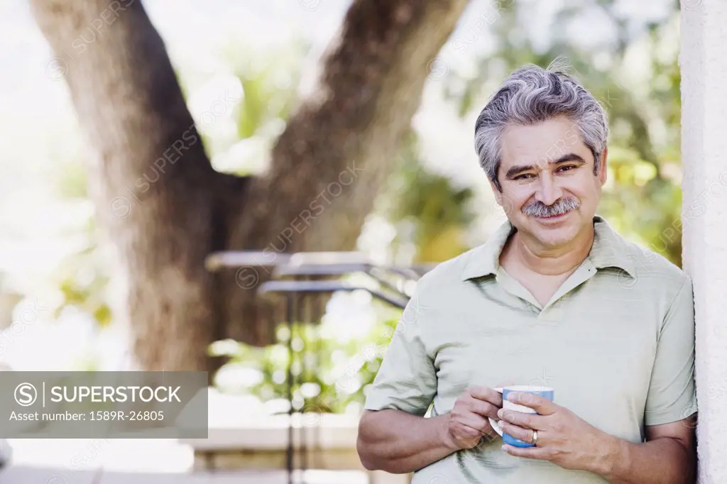 Middle-aged man with coffee smiling outdoors