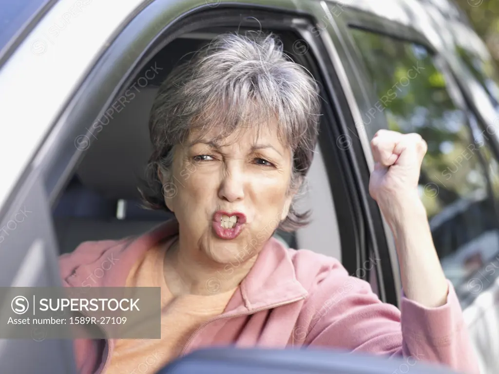 Angry senior Hispanic woman in driverís seat of car