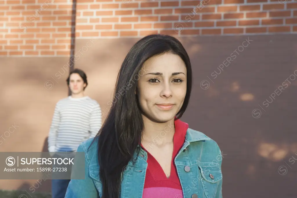 Young Hispanic woman with man in background