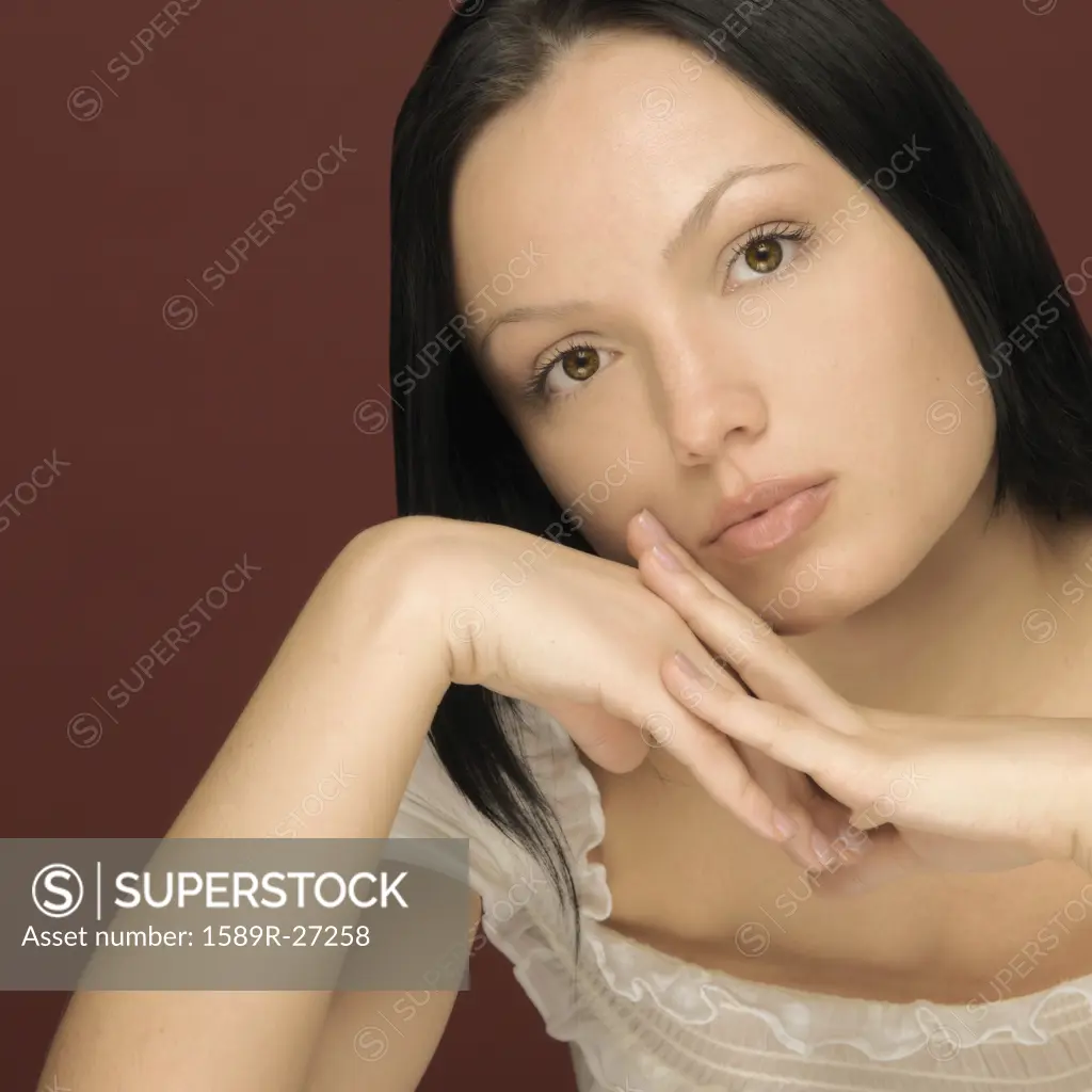 Studio shot of woman leaning face on hands