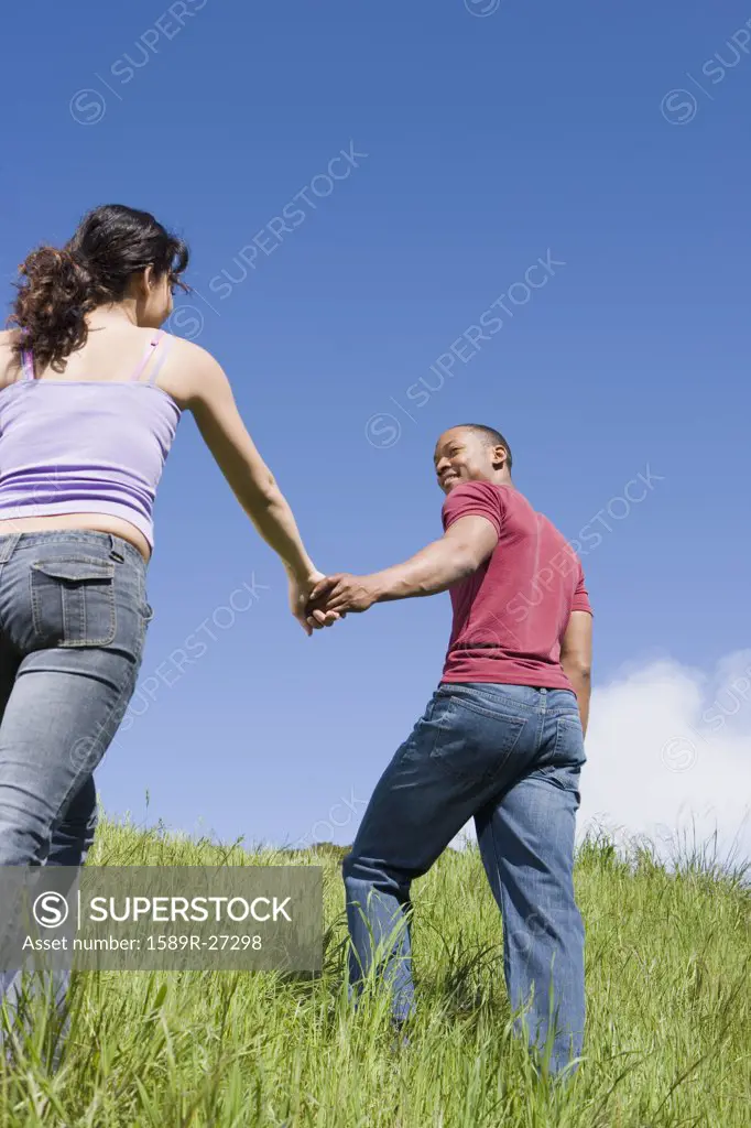 Couple holding hands and walking up hill