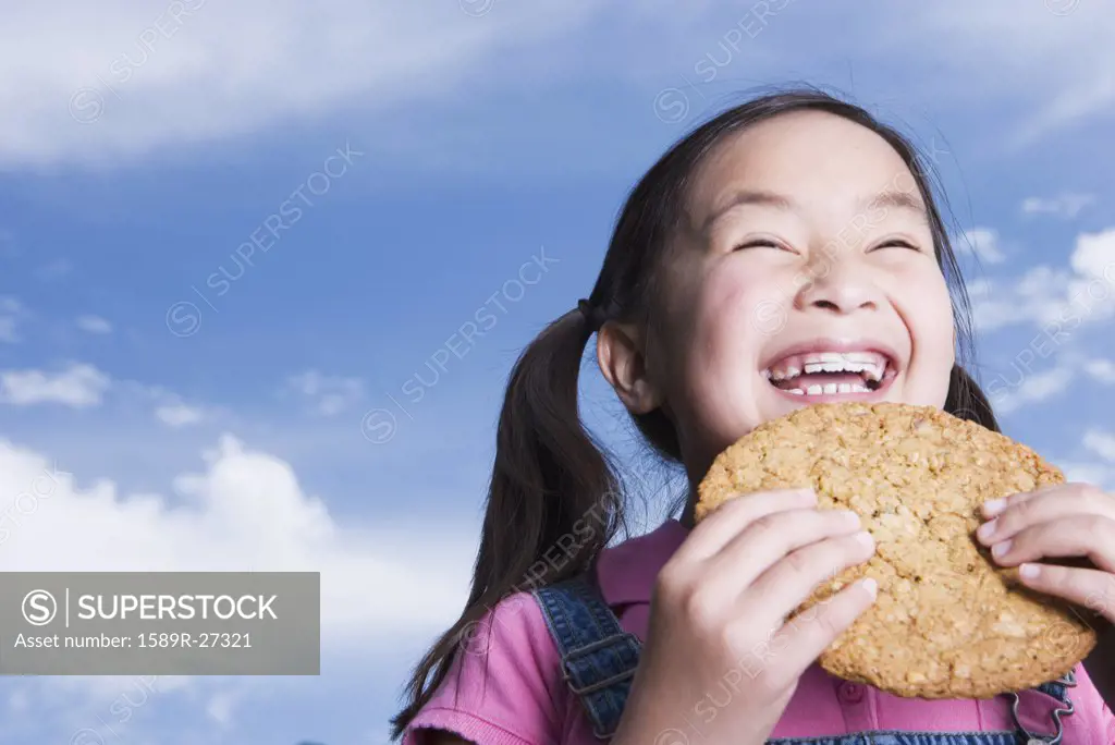 Young Asian girl holding cookie outdoors