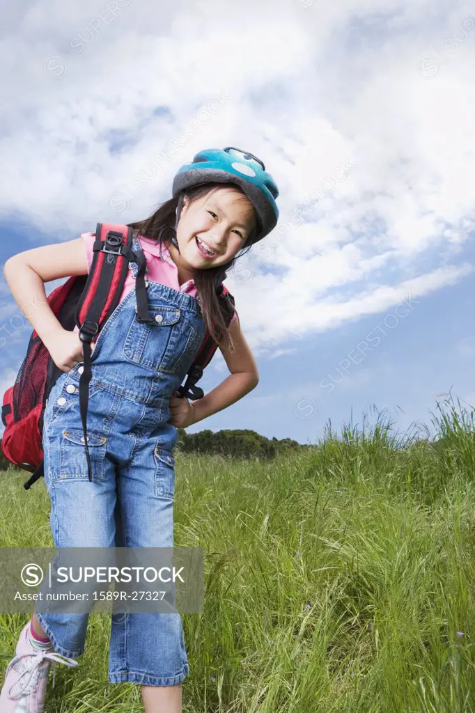 Young Asian girl with backpack and bicycle helmet outdoors