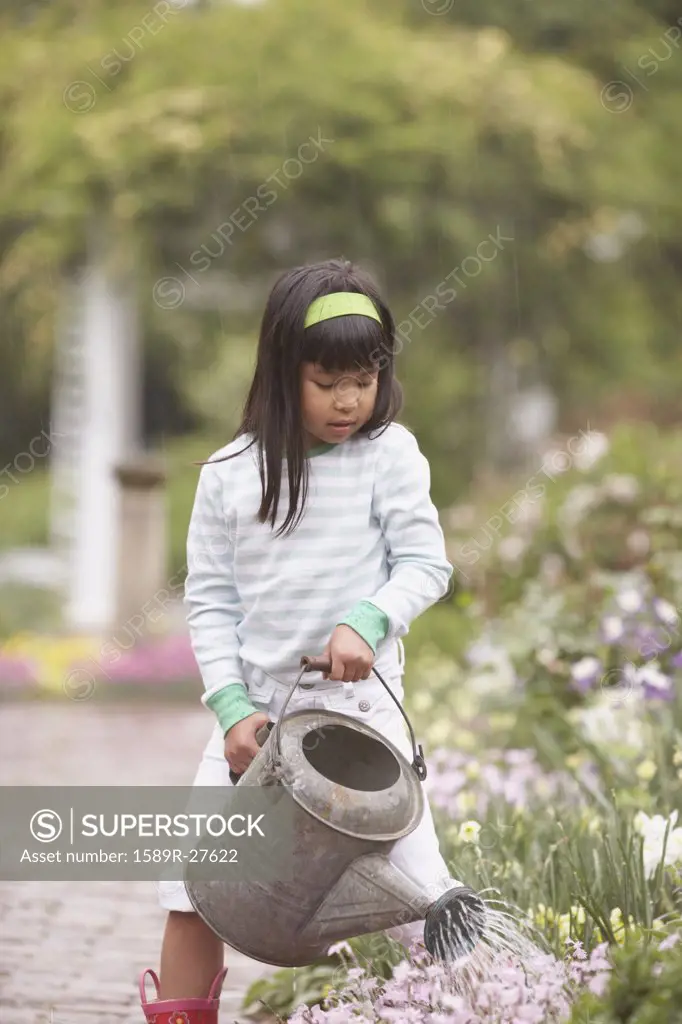 Asian girl using watering can in garden