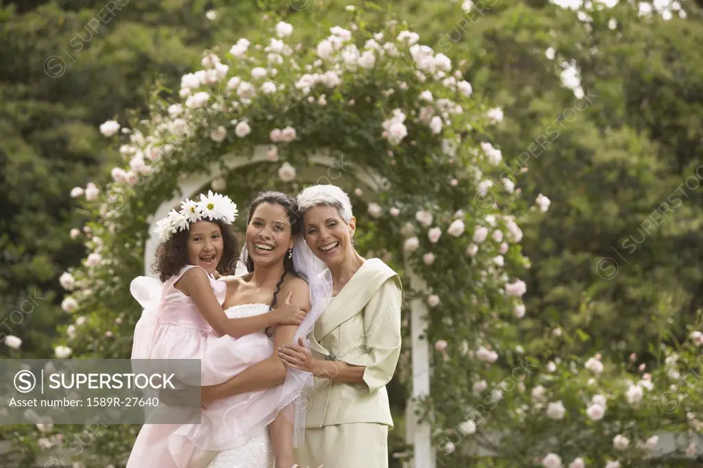 Hispanic bride with mother and young girl smiling