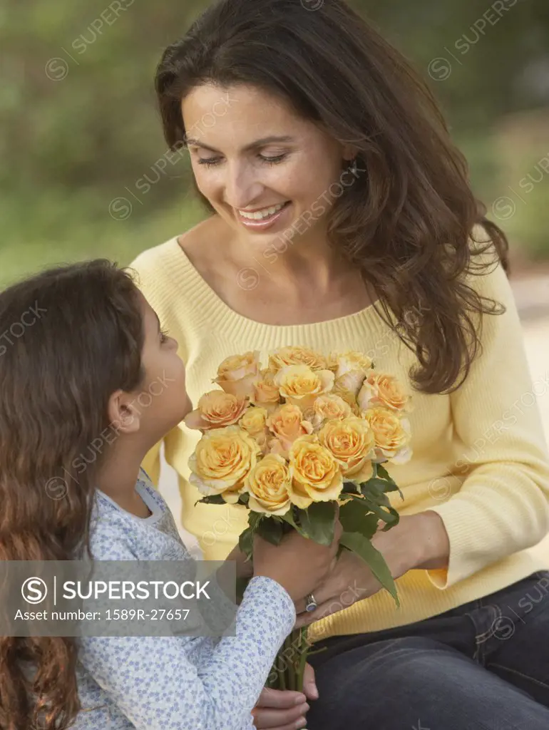 Hispanic daughter giving mother flowers