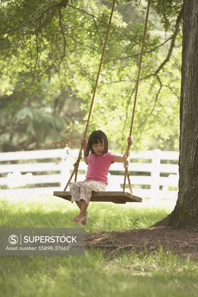 Young Asian girl on swing under tree