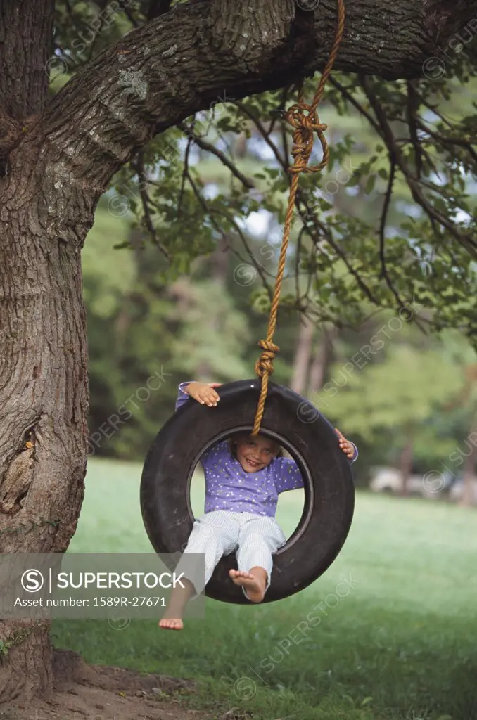 Young girl sitting in tire swing