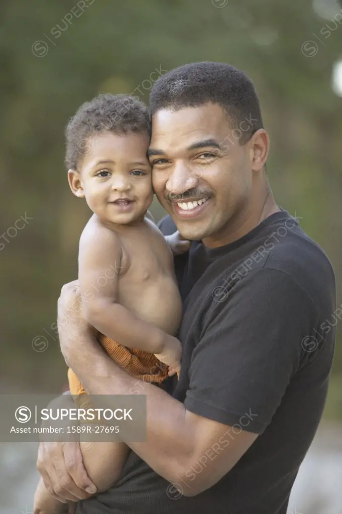 African father holding baby and smiling