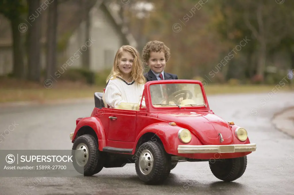 Young boy and girl riding in toy car 
