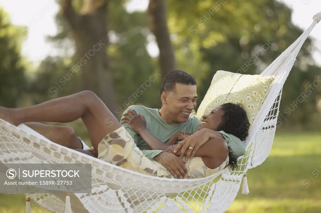 Middle-aged African couple hugging in hammock