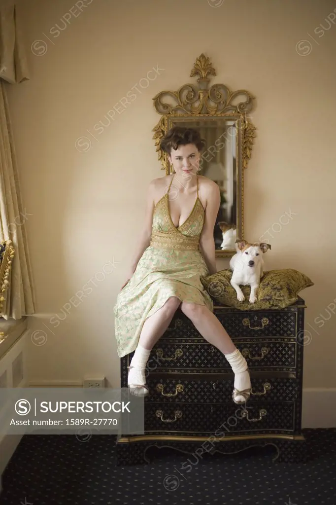 Woman in fancy dress with small dog on dresser