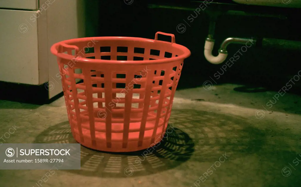 Empty laundry basket on floor in basement