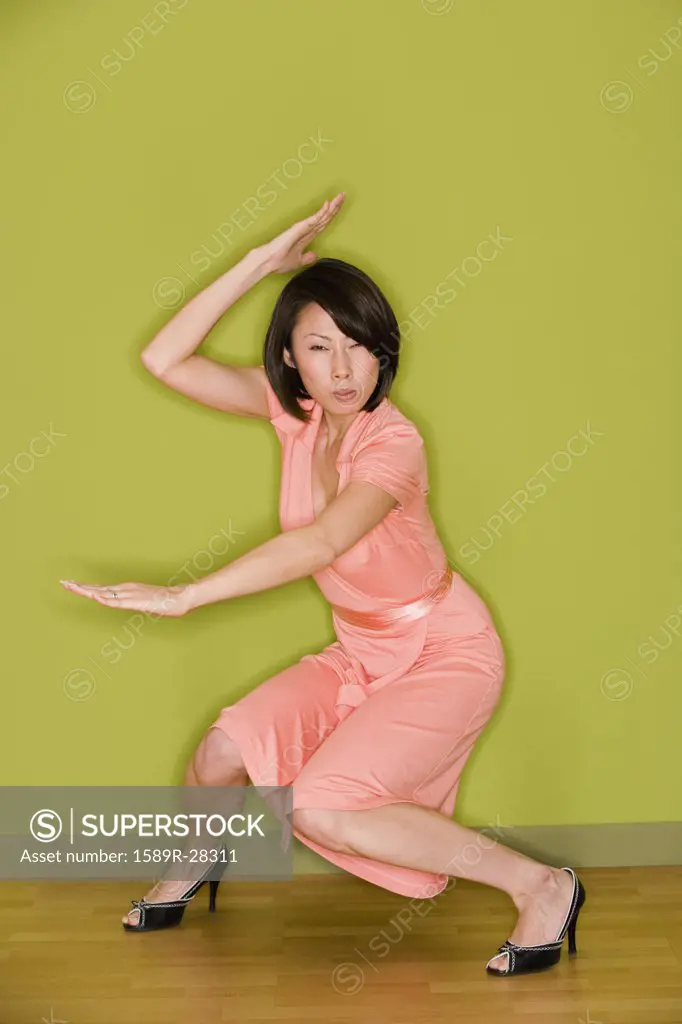 Asian woman in dress doing martial arts move 
